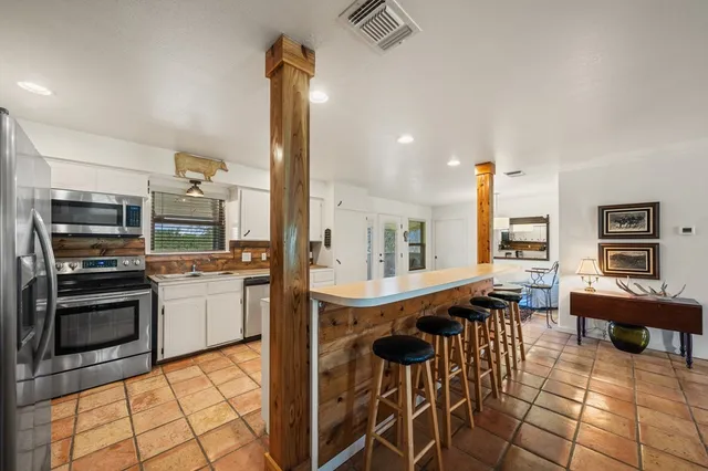 a kitchen with stainless steel appliances kitchen island granite countertop a table chairs sink and cabinets