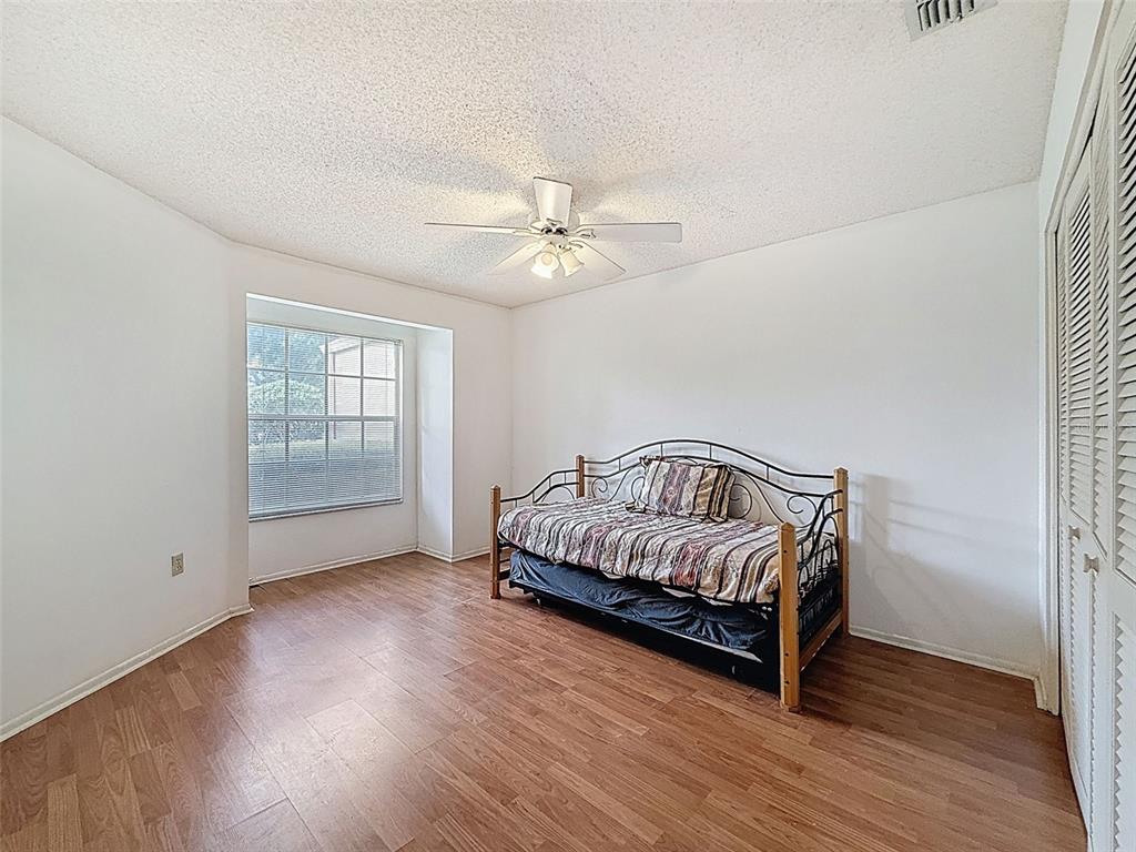 11403 Versailles Lane, Unit E Port Richey, FL 34668 - Photo 12 of 74 a spacious bedroom with a bed and a ceiling fan