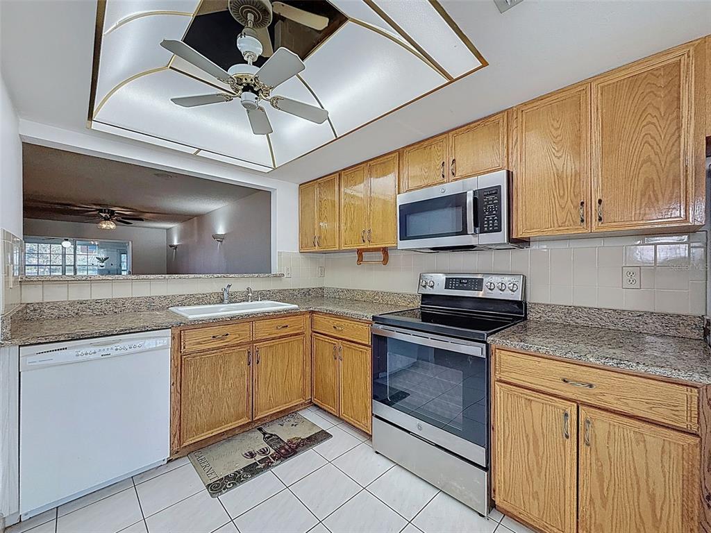 11403 Versailles Lane, Unit E Port Richey, FL 34668 - Photo 20 of 74 a kitchen with stainless steel appliances granite countertop a sink and cabinets
