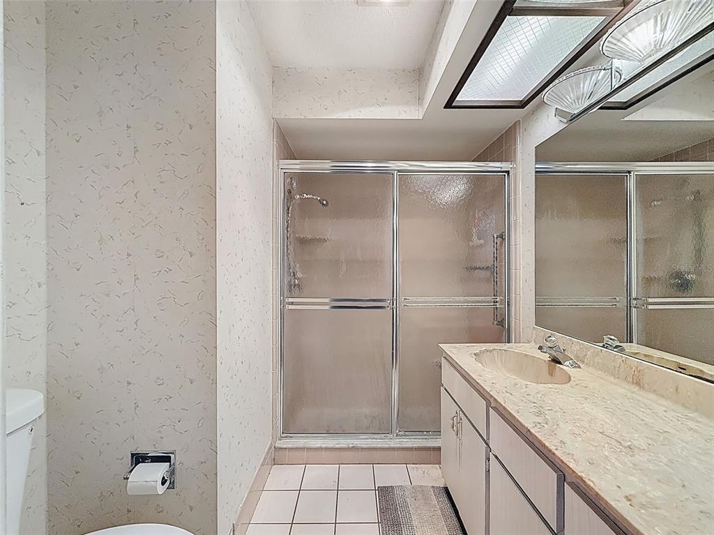 11403 Versailles Lane, Unit E Port Richey, FL 34668 - Photo 25 of 74 a bathroom with a granite countertop sink mirror and shower