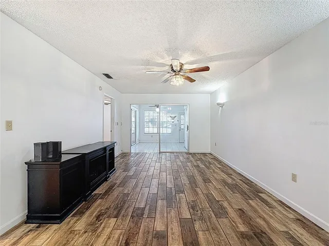 a view of a room with wooden floor and ceiling fan