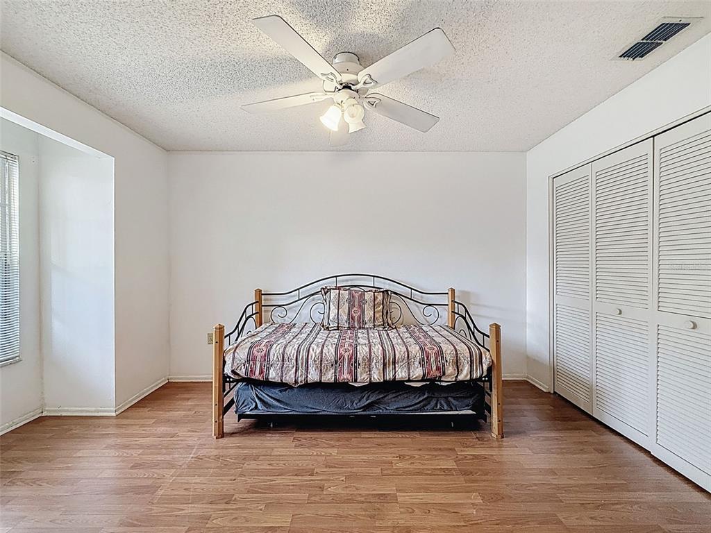 11403 Versailles Lane, Unit E Port Richey, FL 34668 - Photo 34 of 74 a bedroom with a bed and a ceiling fan