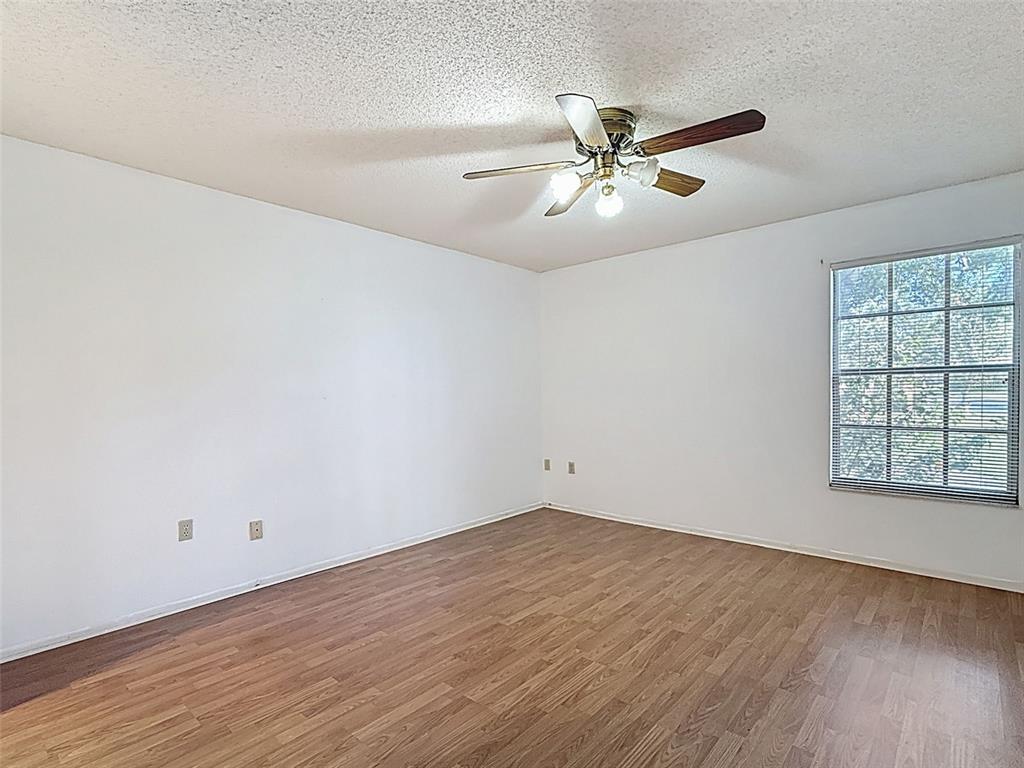 11403 Versailles Lane, Unit E Port Richey, FL 34668 - Photo 37 of 74 an empty room with wooden floor fan and windows