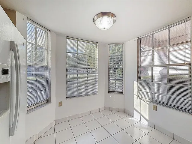 an empty room with wooden floor chandelier fan and windows
