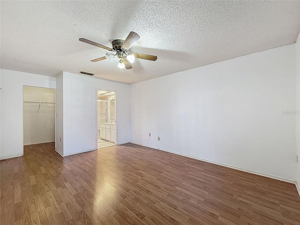 11403 Versailles Lane, Unit E Port Richey, FL 34668 - Photo 9 of 74 an empty room with wooden floor chandelier fan and windows