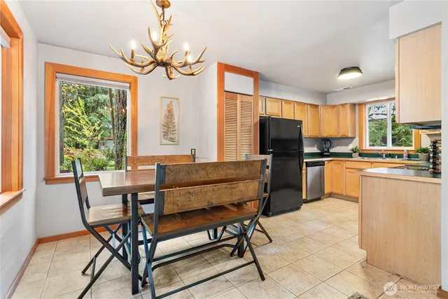 a kitchen with granite countertop a refrigerator a stove top oven a sink dishwasher and dining table with wooden floor