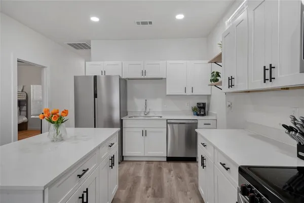 a kitchen with a sink white cabinets and stainless steel appliances