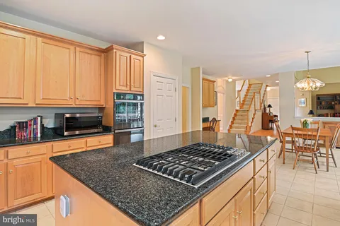 a kitchen with stainless steel appliances granite countertop a stove top oven a sink a dining table and chairs