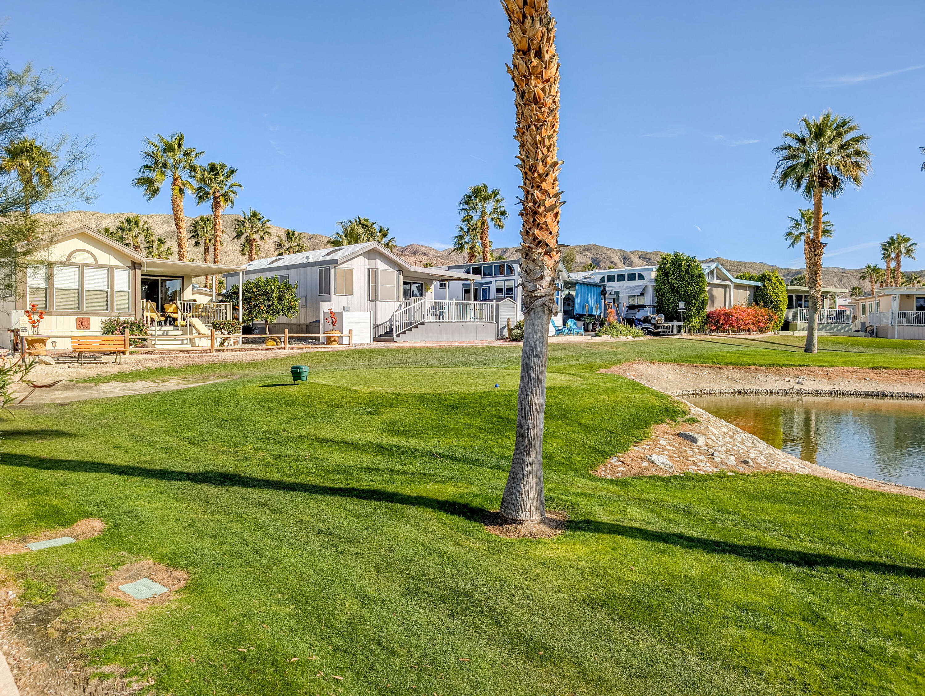70200 Dillon Road, Unit 590 Desert Hot Springs, CA 92241 - Photo 14 of 42 a view of a lake with a big yard and palm trees