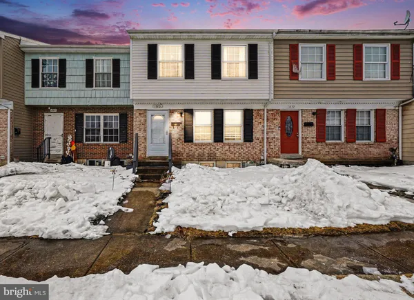 a front view of a house with a yard covered with snow