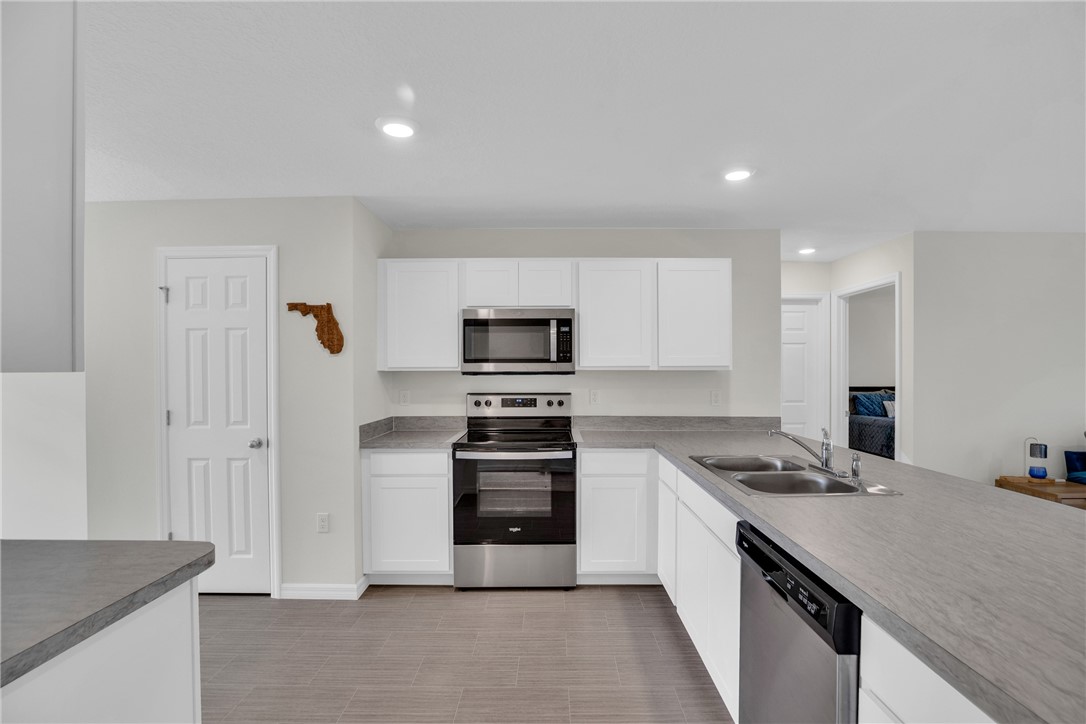 938 Clearmont Street Sebastian, FL 32958 - Photo 11 of 36 a kitchen with stainless steel appliances granite countertop a stove top oven a sink and a refrigerator