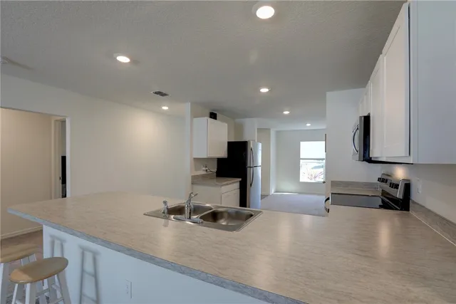 a view of a kitchen with kitchen island a sink stainless steel appliances and a counter top space