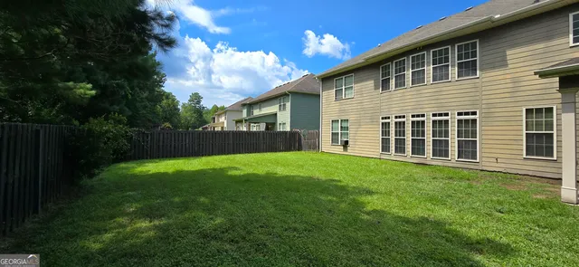 a view of a backyard with plants and large tree