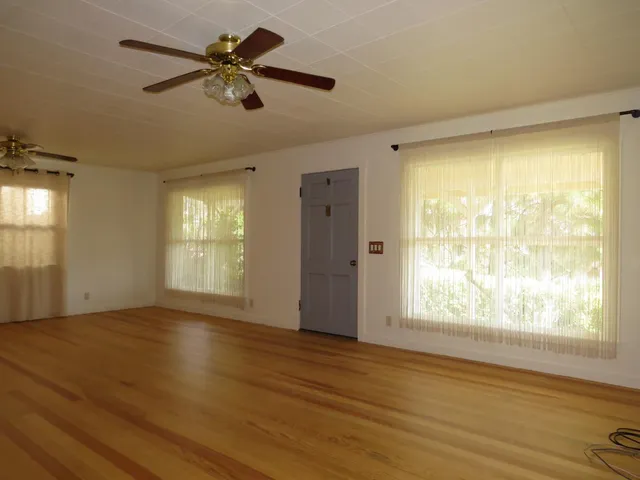 a view of an empty room with a window and wooden floor