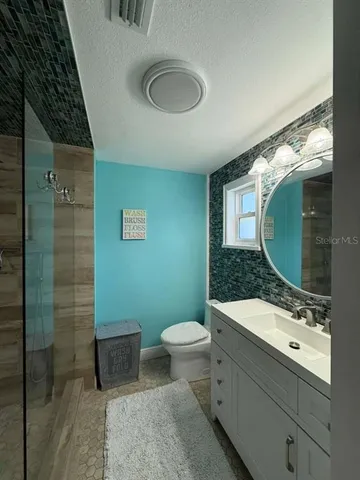 a bathroom with a granite countertop sink a toilet and a mirror