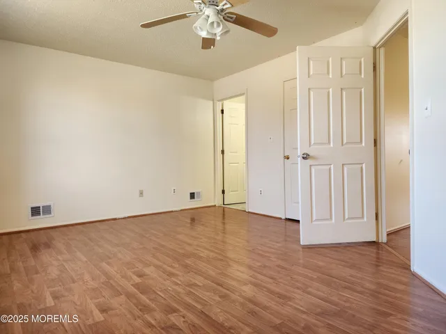 an empty room with wooden floor and ceiling fan
