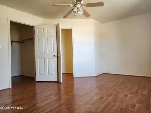 an empty room with wooden floor closet and windows