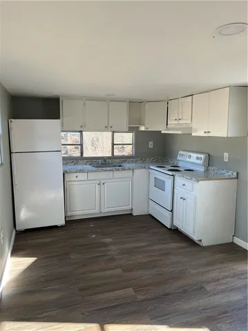 a kitchen with a sink a refrigerator and white cabinets
