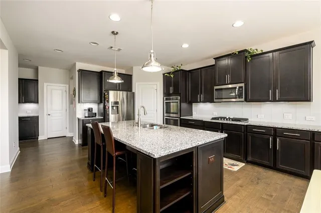 a kitchen with granite countertop stainless steel appliances a stove sink and cabinets