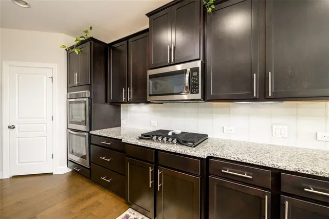 a kitchen with stainless steel appliances a table chairs sink and window