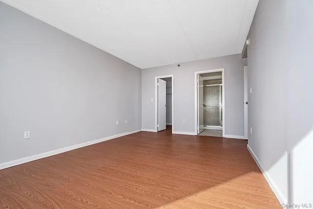 a view of an empty room with wooden floor and closet