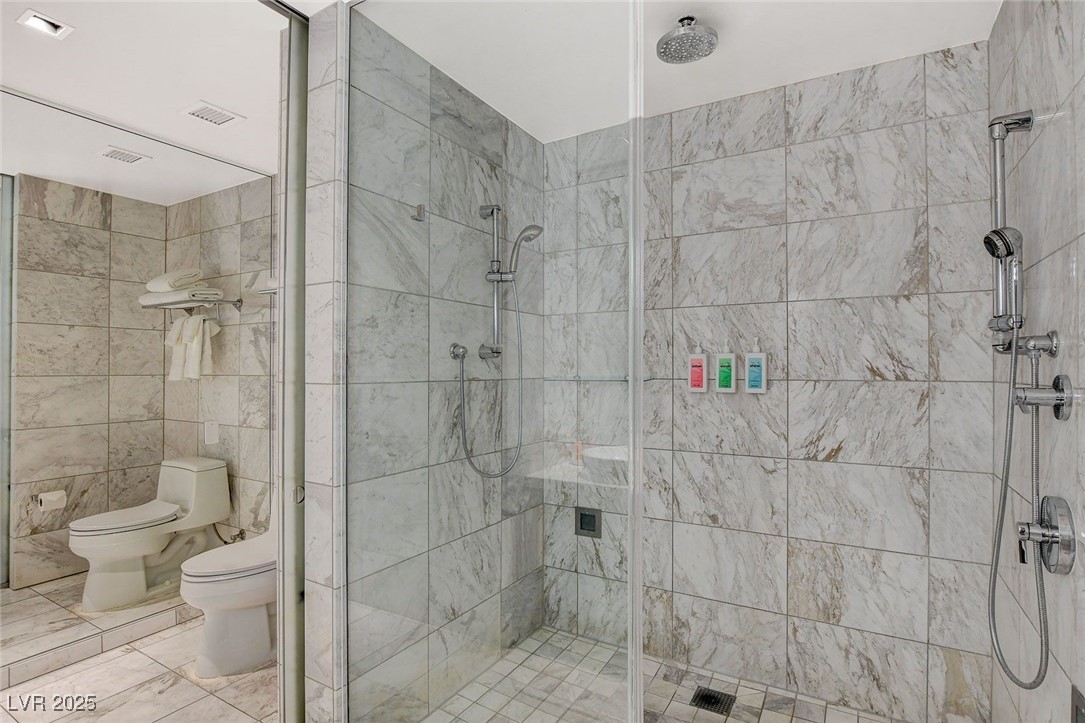 4381 West Flamingo Road, Unit 2202 Las Vegas, NV 89103 - Photo 26 of 40 Full bathroom with a stall shower, tile walls, and marble finish floors