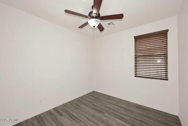 an empty room with wooden floor a ceiling fan and closet