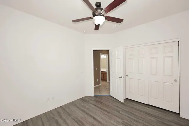 an empty room with wooden floor and ceiling fan