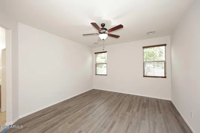 a view of room with hardwood floor and a ceiling fan