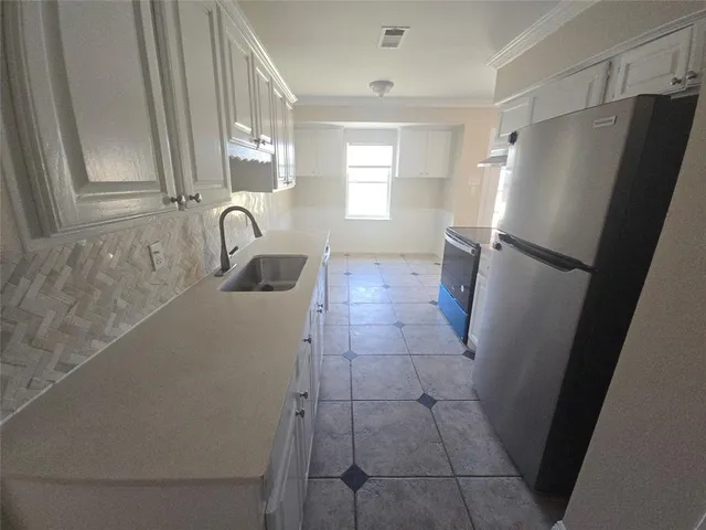 a bathroom with a sink a refrigerator a window and vanity