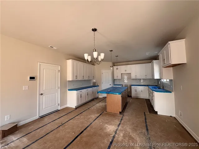 a large white kitchen with a white countertops a stove and a chandelier