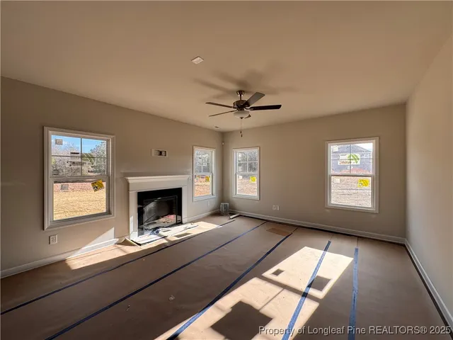 a living room with a fireplace windows and a ceiling fan
