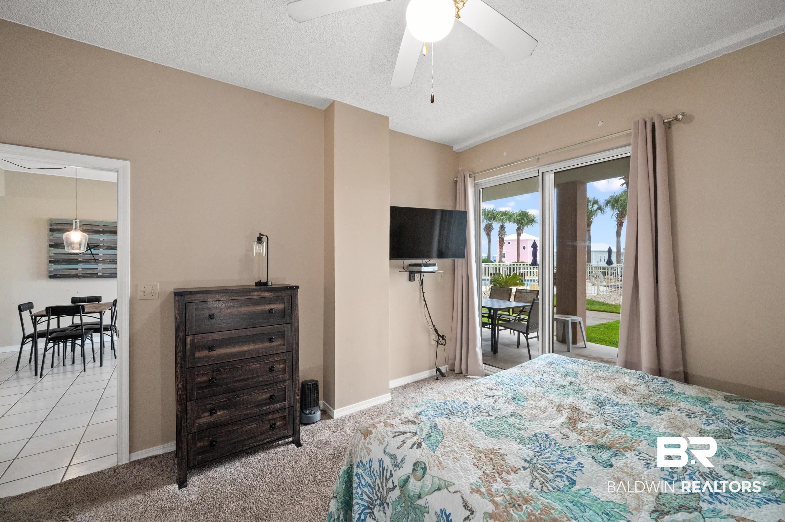 1380 Fort Morgan Road, Unit 106 Gulf Shores, AL 36542 - Photo 7 of 20 Carpeted bedroom with access to exterior, a textured ceiling, and baseboards
