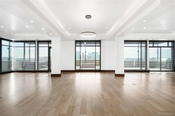 an empty room with wooden floor and floor to ceiling window