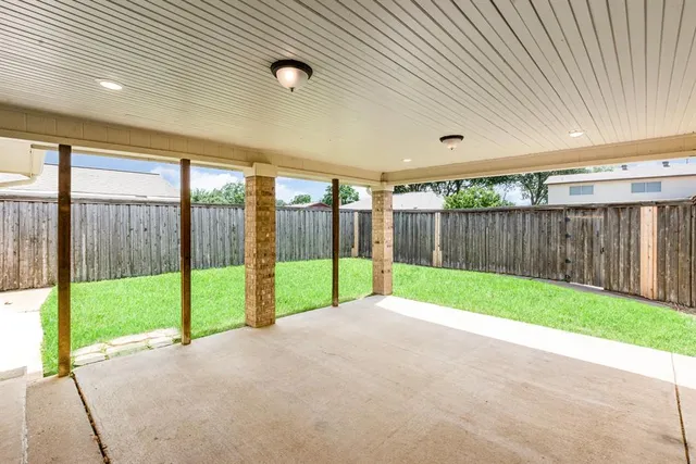a view of a backyard with floor to ceiling window and wooden fence