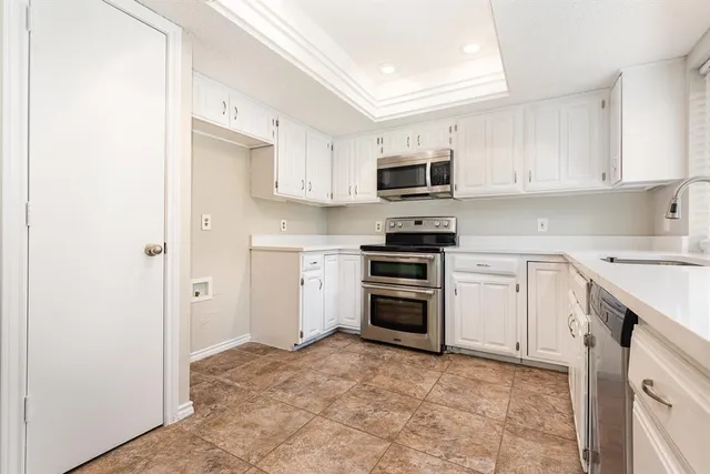 a kitchen with kitchen island a refrigerator stove and white cabinets