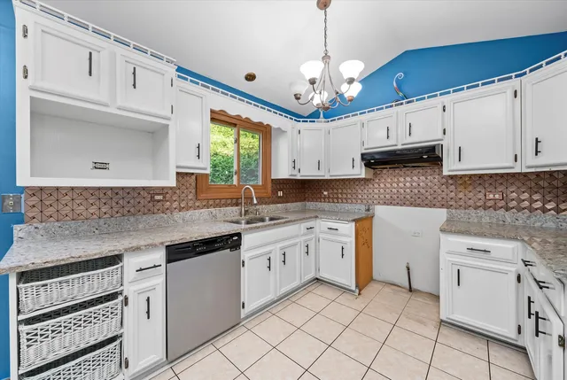 a kitchen with kitchen island granite countertop a stove a sink and white cabinets