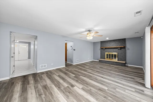 a view of an empty room with a fireplace and a chandelier fan