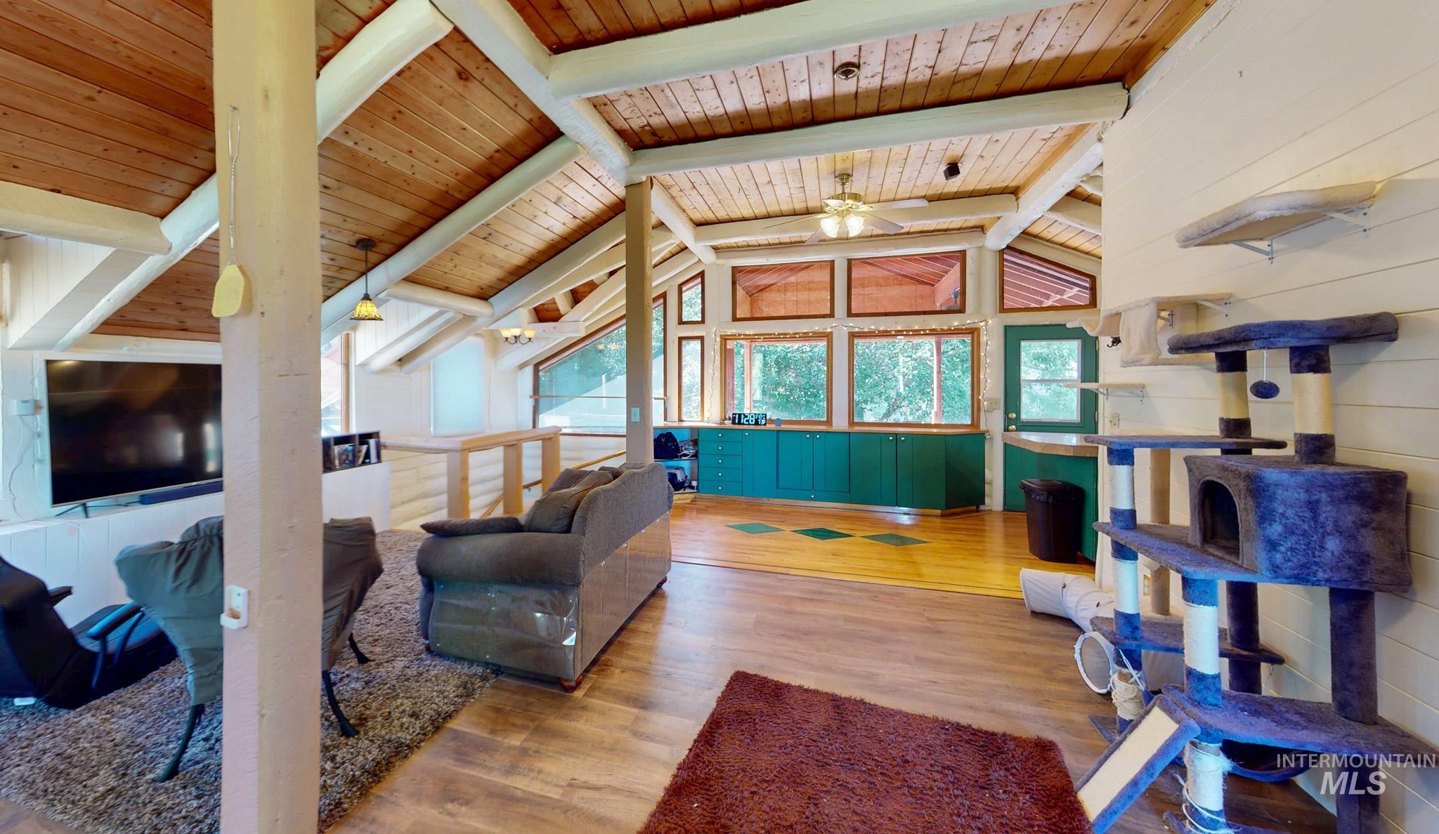 863 Pottery Road Bliss, ID 83314 - Photo 4 of 45 Expansive open-concept room featuring a vaulted wood-paneled ceiling with exposed beams, wood-finish flooring, and a bank of large windows
