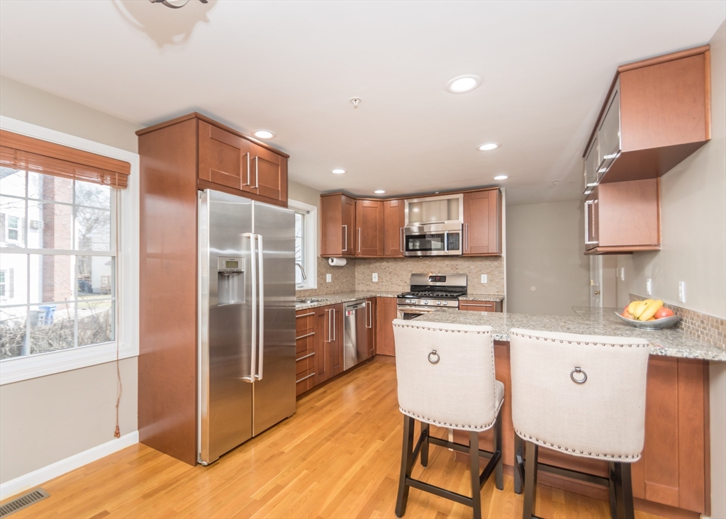 985 Trapelo Road, Unit 23 Waltham, MA 02452 - Photo 5 of 27 a kitchen with stainless steel appliances kitchen island granite countertop a refrigerator a stove a sink a dining table and chairs