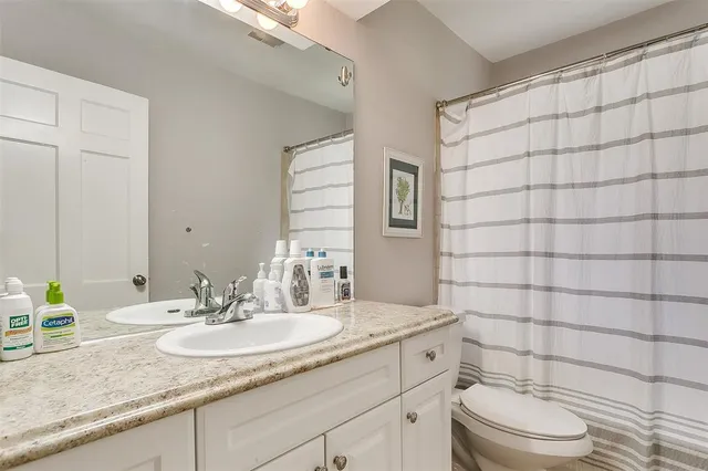 a bathroom with a granite countertop sink a toilet and a mirror