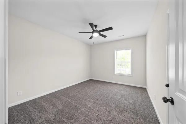 an empty room with a window and a ceiling fan