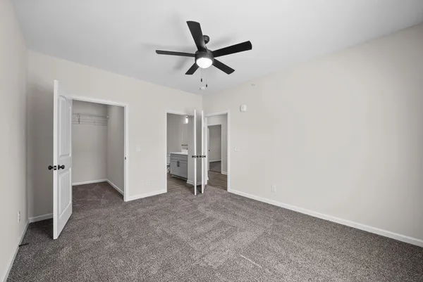 an empty room to closet and a ceiling fan