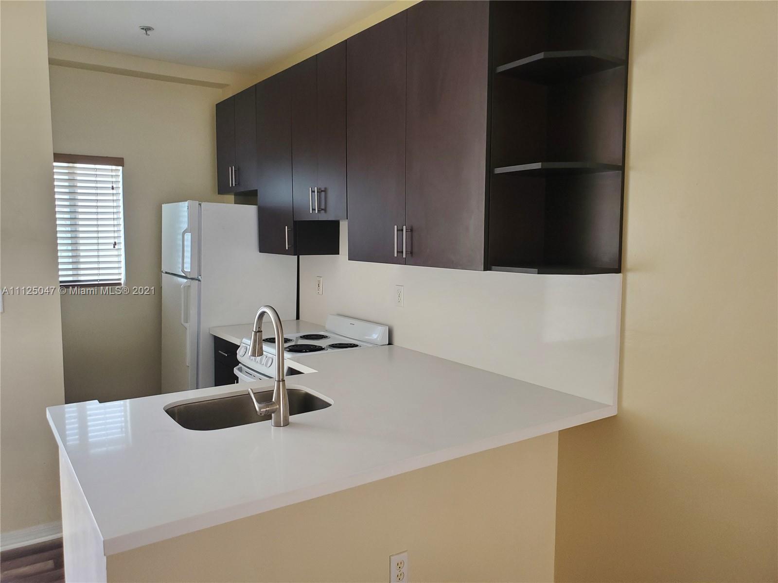 928 Southwest 3rd Street, Unit 203 Miami, FL 33130 - Photo 7 of 16 a kitchen with a sink and a refrigerator