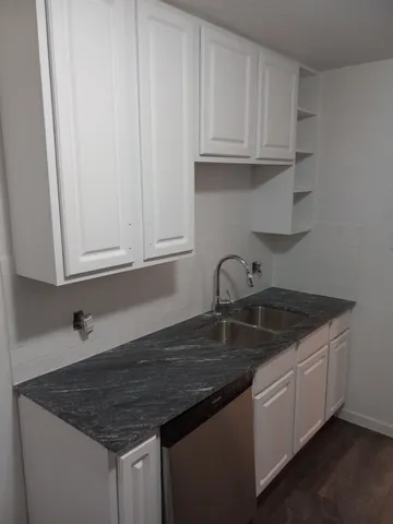 a kitchen with granite countertop a sink dishwasher a stove and white cabinets
