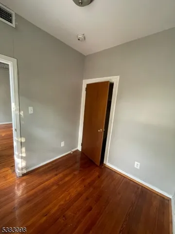 an empty room with wooden floor and entrance