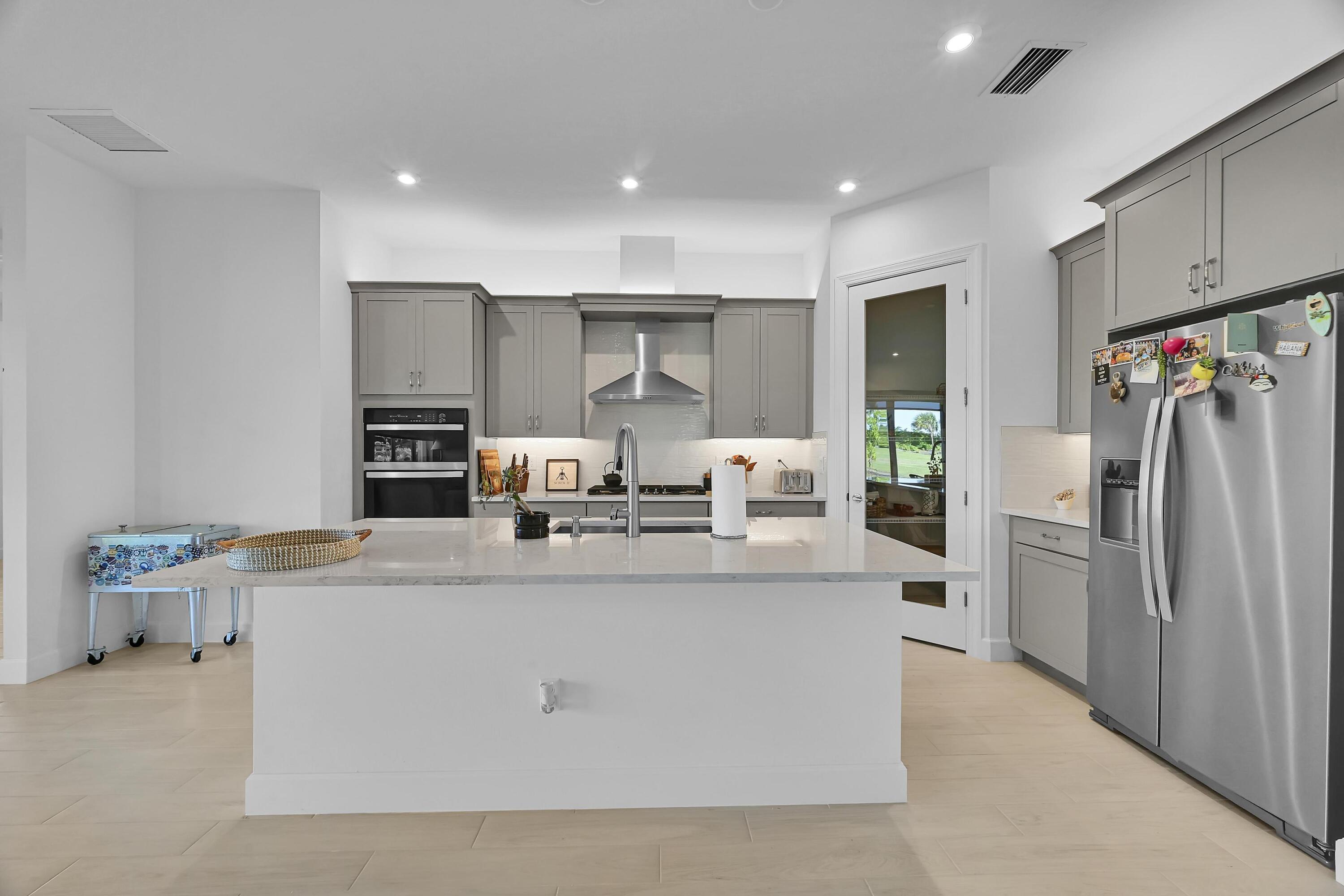 14185 Southwest Daphne St Port Port St. Lucie, FL 34987 - Photo 5 of 46 a large kitchen with stainless steel appliances kitchen island a stove a refrigerator a oven and a sink with large cabinets