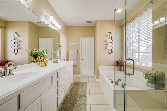 a spacious bathroom with a double vanity sink a large mirror and shower