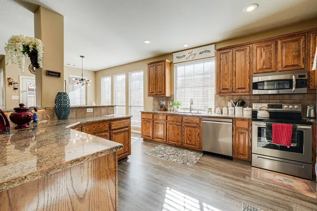 a kitchen with stainless steel appliances granite countertop a stove a sink and a microwave