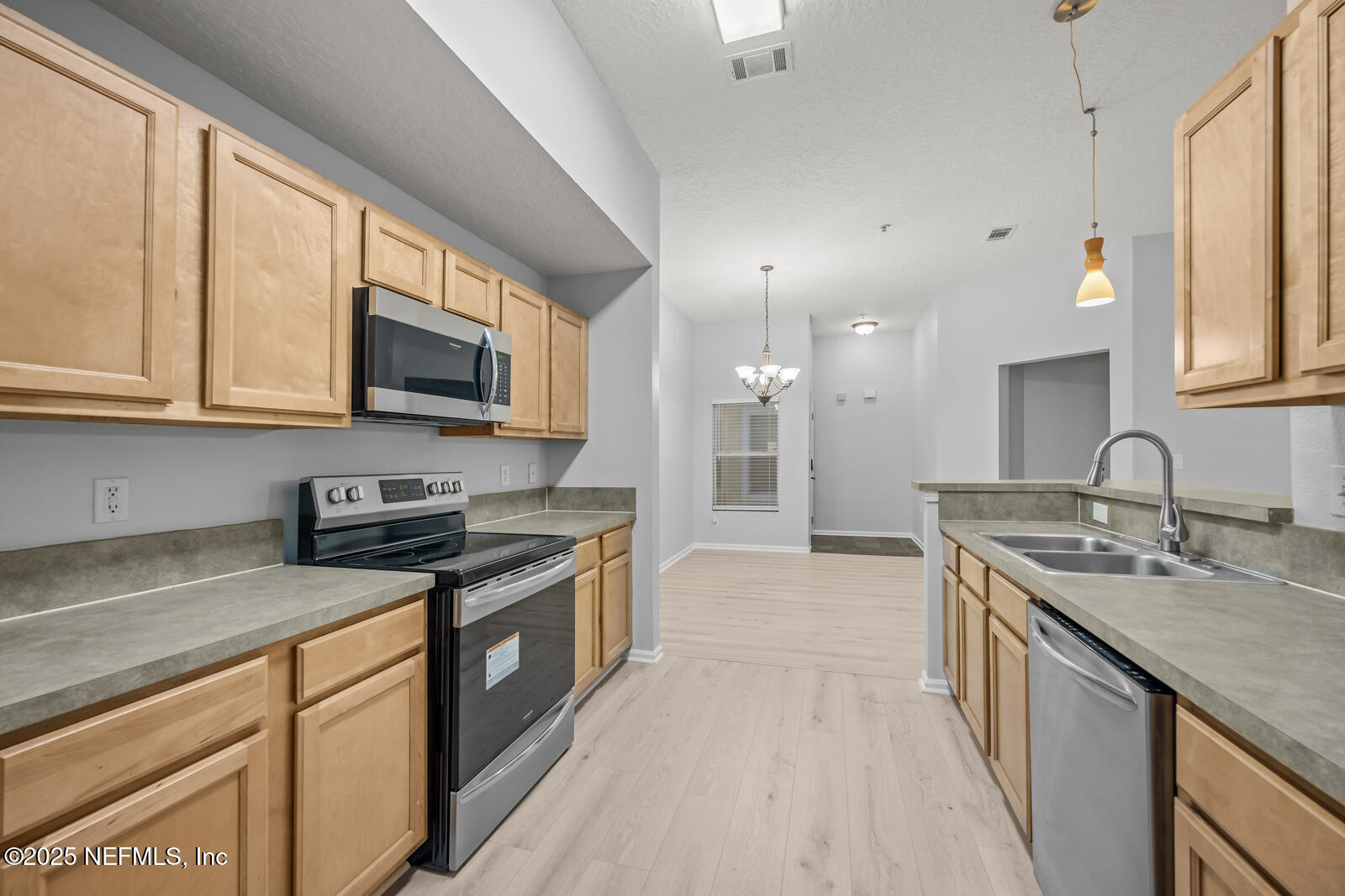 7920 Merrill Road West, Unit 1604 Jacksonville, FL 32277 - Photo 8 of 30 a kitchen with stainless steel appliances granite countertop a sink stove microwave refrigerator and cabinets
